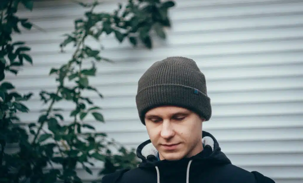 man standing in front of house wearing hoodie and beanie